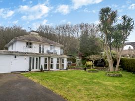 A two-story house with glass balcony and garden with trees and grass at Broadsands in Paignton