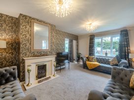 A living room with two grey tufted sofas a fireplace a mirror a television and patterned wallpaper at Broadsands in Paignton