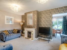 A living room with a blue sofa a fireplace and a television next to a dining area at Broadsands in Paignton