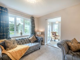 A living room with two sofas and pillows next to a window and an armchair in an adjacent room at Broadsands Paignton