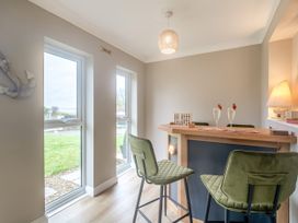 A small bar area with two green bar stools two glasses with strawberries on the rim and game pieces on the bar at Broadsands Paignton