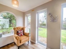 A room with a tan armchair featuring a union jack pillow near windows and a wall anchor decoration at Broadsands in Paignton