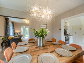 A dining room with a wooden table set with plates and a vase of flowers at Broadsands in Paignton