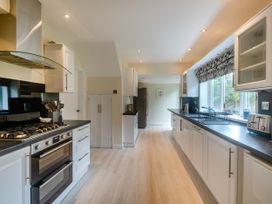 A long kitchen with white cabinets black countertops a gas stove oven a toaster and a large window at Broadsands in Paignton