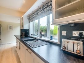 A kitchen countertop with a sink a toaster a kettle and a window with patterned blinds at Broadsands Paignton