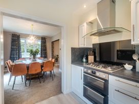 A kitchen with a gas stove and oven next to a dining room with a wooden table and orange chairs at Broadsands in Paignton