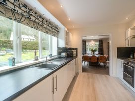 A kitchen with a black countertop a stainless steel sink and window overlooking a garden with chairs at Broadsands in Paignton