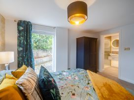 A bedroom with a patterned bedspread and pillows a dark wardrobe and a view of a bathroom at Broadsands in Paignton