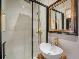 A bathroom with a glass shower enclosure white sink with gold faucet and a framed mirror at Broadsands in Paignton