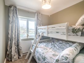 A bedroom with bunk beds and patterned curtains by a window at Broadsands in Paignton