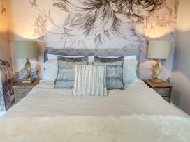 A bedroom with a bed with multiple pillows flanked by bedside tables and lamps at Broadsands in Paignton