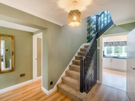 A hallway with carpeted stairs and a light fixture next to a doorway leading to a kitchen at Broadsands in Paignton