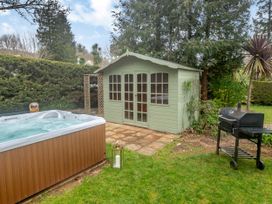 A garden with a wooden shed a hot tub a barbecue grill and green grass at Broadsands in Paignton