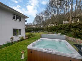 A garden with a hot tub lounge chairs and a white house at Broadsands in Paignton
