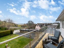 A balcony with two chairs and a small table overlooking a grassy yard and houses at Broadsands in Paignton