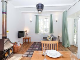 A living room with a wood stove, sofa, and television at Nest Cottage in St Tudy