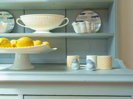 A kitchen shelf with a bowl, plate, decorative frogs, and lemons at Y Graiglwyd Bull Bay near Amlwch