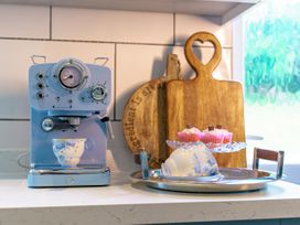 An espresso machine with a cup and cupcakes on a tray at Y Graiglwyd in Bull Bay near Amlwch