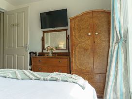 A bedroom with a bed, dresser, mirror, and television at Y Graiglwyd Bull Bay near Amlwch