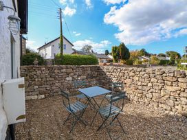 An outdoor area with a table and chairs enclosed by a stone wall at Cwtch in Mold