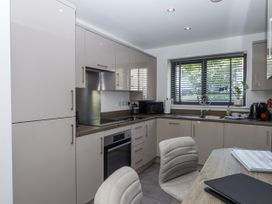 A kitchen with cabinets, stove, sink and a table at Driftwood in Torquay