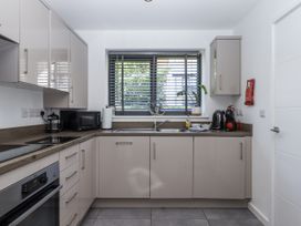 A kitchen with cabinets, sink, microwave and window at Driftwood in Torquay