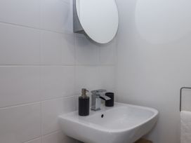 A sink with a mirror and soap dispenser at Driftwood in Torquay