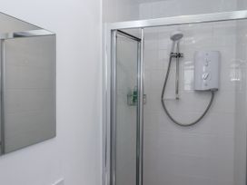 A shower with a water heater and mirror at Driftwood in Torquay