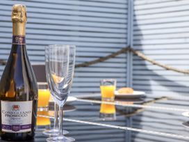 An outdoor dining area with a bottle of Prosecco and glasses at Driftwood in Torquay