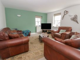 A living room with brown leather sofas and a television at Awen Ingli in Newport, Pembrokeshire