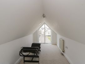 A loft space with a chair and a view to a balcony at Awen Ingli, Newport, Pembrokeshire