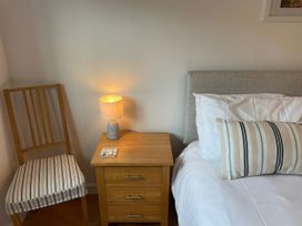 A bedroom with a bed, nightstand, lamp, chair and booklet at Broadleys in Swanage
