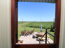 A view of a patio with chairs and a table from a doorway at Sweet Caroline Shepherd’s Hut Low Marnham near Sutton-On-Trent