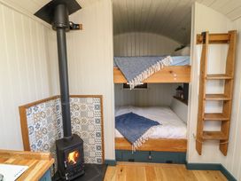 A bedroom with a bunk bed and wood-burning stove at Sweet Caroline Shepherd’s Hut Low Marnham near Sutton-On-Trent