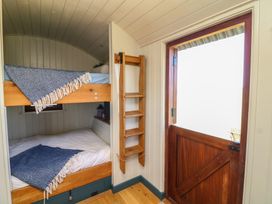 A bedroom with bunk beds and a wooden door at Sweet Caroline Shepherd’s Hut in Low Marnham near Sutton-On-Trent