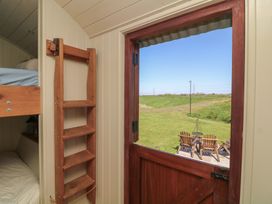 A view from inside a hut showing a wooden ladder and an outdoor seating area at Sweet Caroline Shepherd’s Hut Low Marnham near Sutton-On-Trent
