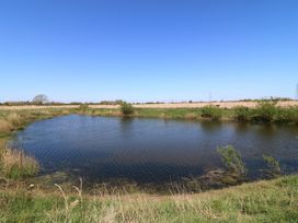 A pond with grass and trees at Sweet Caroline Shepherd’s Hut Low Marnham near Sutton-On-Trent