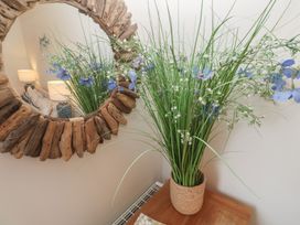 A vase with flowers on a table and a mirror in the living room at Upper Deck Truro