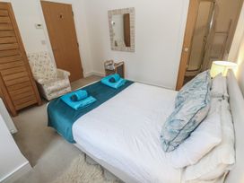 A bedroom with a bed, chair, and mirror at Upper Deck, Truro