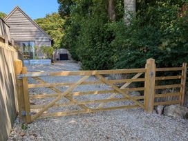 A wooden gate leading to a gravel driveway at Roman Lodge in Osmington