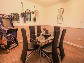 A dining room with a glass table and arcade game at 8 Beechwood Close, Bowness-On-Windermere