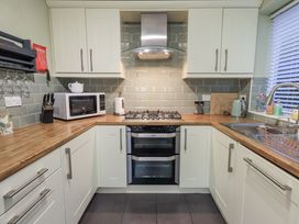 A kitchen with a stove, microwave, and sink at 8 Beechwood Close Bowness-On-Windermere