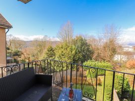 A balcony with a bottle and glasses overlooking a garden at Lake View in Bowness-On-Windermere