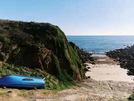 A rocky shore with a blue boat at Three Chimneys in St. Levan near Porthgwarra