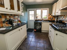 A kitchen with a washing machine and cooker at Cove Cottage Weymouth