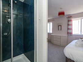 A shower and bedroom with storage at Cove Cottage in Weymouth
