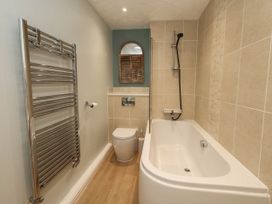 A bathroom with a bathtub, toilet, and towel radiator at Cove Cottage in Weymouth
