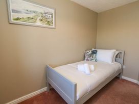 A bedroom with a single bed and wall art at Cove Cottage in Weymouth