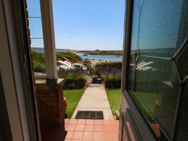 A view from a doorway towards a pathway and water at Cove Cottage in Weymouth