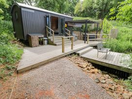 A shepherd's hut with decking and steps at The Shepherds Hut at Bridge Lake Farm & Fishery Chacombe